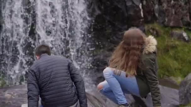 滝の前に座っている 2 人の友人 — ストック動画