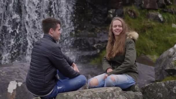 Dos amigos disfrutan de la maravillosa naturaleza de Irlanda frente a una cascada — Vídeos de Stock