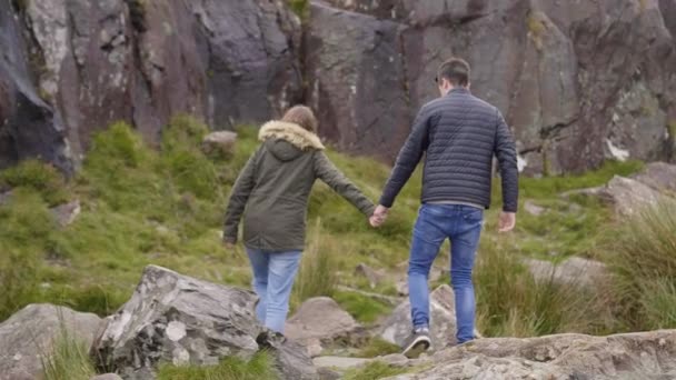 İki arkadaş el içinde el dağların üzerinden yürümek — Stok video