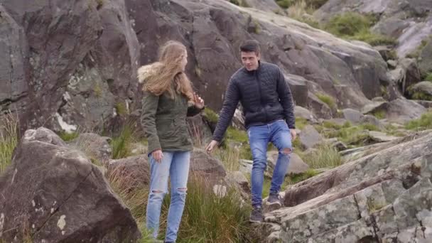 Zwei Freunde klettern eine felsige Landschaft hinunter — Stockvideo