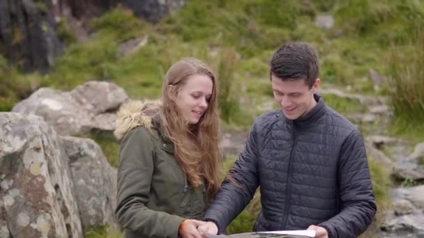Casal jovem em uma viagem - verificando as instruções em um mapa — Vídeo de Stock