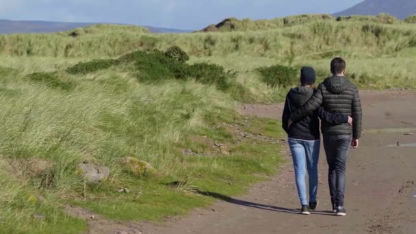 Два влюбленных друга наслаждаются расслабляющей прогулкой по зеленой траве — стоковое видео
