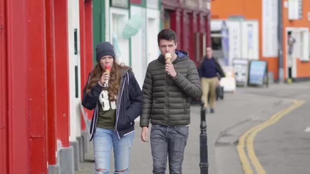 Pareja joven camina por las calles y come helado — Vídeos de Stock