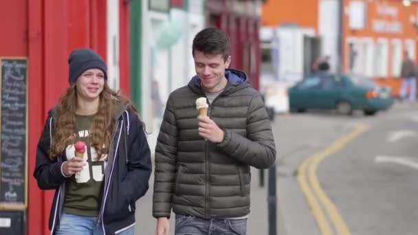 Щаслива пара їсть морозиво, ходячи по вулицях — стокове відео