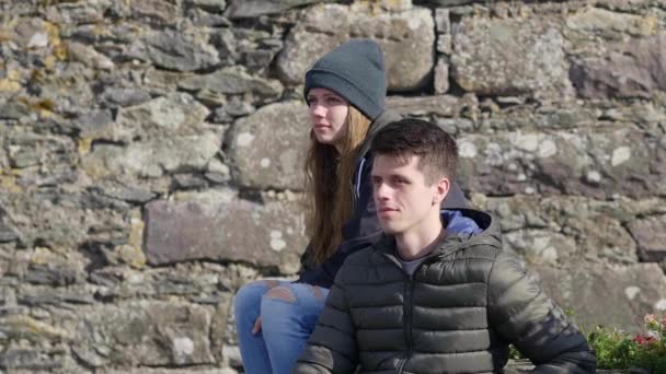 Νεαρό ζευγάρι χαλαρώνει σ ' ένα παγκάκι — Αρχείο Βίντεο