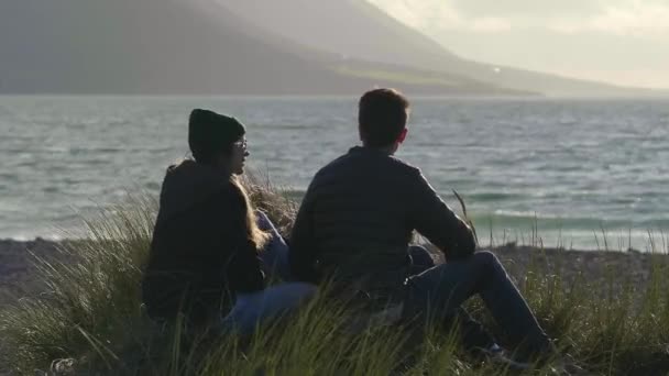 Twee personen aan het water in reed gras zitten — Stockvideo