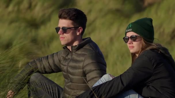 Two friends enjoy their travel to Ireland while sitting in reed grass — Stock Video