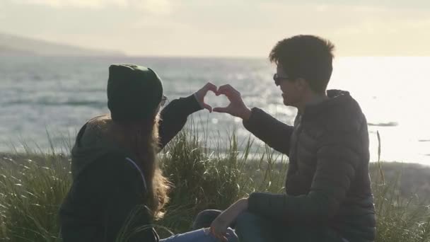Pasangan membentuk bentuk hati dalam cahaya latar belakang — Stok Video
