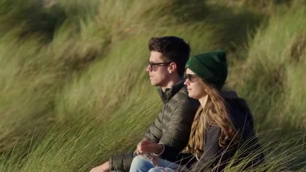 Casal relaxa enquanto sentado na grama junco — Vídeo de Stock