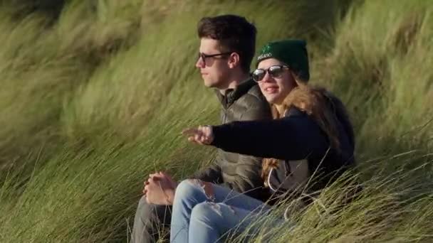 Szczęśliwa para siedzi w trawie reed na nabrzeżu — Wideo stockowe