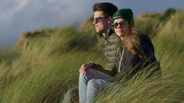 Couple heureux se détend à l'océan tout en étant assis dans l'herbe de roseau — Video