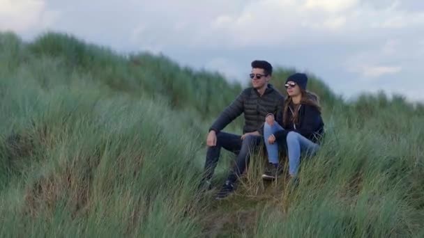 Dwóch przyjaciół siedzieć na wydmach trawiastą zachodnim wybrzeżu Irlandii — Wideo stockowe