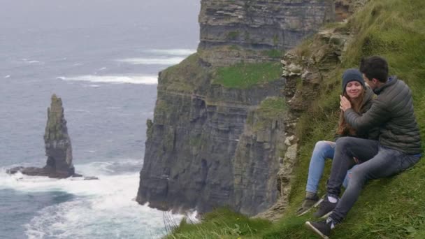 Två vänner i kärlek vid Cliffs of Moher på Irland - hisnande landskap — Stockvideo