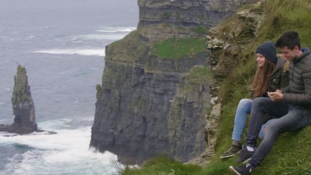 Twee vrienden reizen naar Ierland - zitten op de top van de kliffen van Moher — Stockvideo