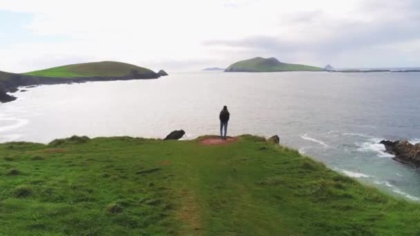 Chica se encuentra en el borde de un acantilado en la costa oeste de Irlanda — Vídeos de Stock