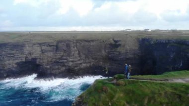 İrlandalı sahilinde uçurumların kenarında duran genç çift