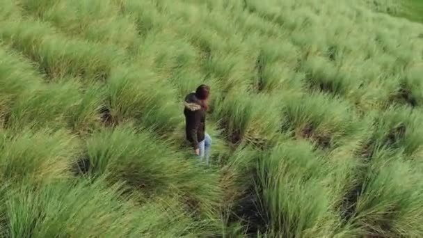 En tjej går genom djupa gräsplaner som njuter av naturen — Stockvideo