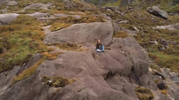 Flyg från en tjej som sitter på en sten — Stockvideo