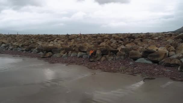 Giovane coppia si siede su una roccia e gode la vista sull'oceano — Video Stock