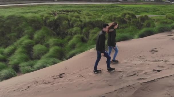 Mladý pár chlapu písečných dun na irské pobřeží kochat výhledem na oceán — Stock video