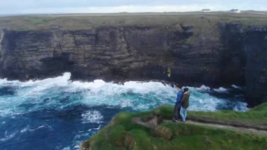 Genç çift İrlandalı Batı sahilinde uçurumun kenarında duruyor