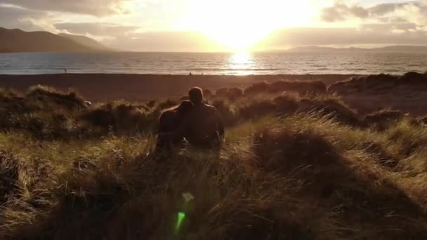 Pareja joven enamorada en la playa al atardecer — Vídeo de stock