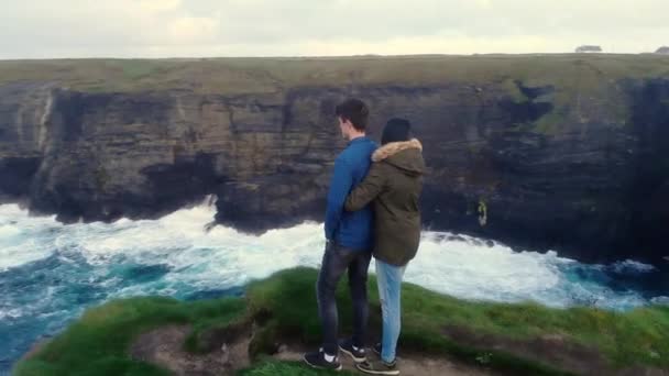 Pareja joven enamorada parada en los acantilados de la costa oeste de Irlanda — Vídeo de stock