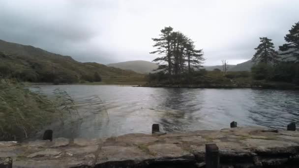 Chica joven se para en un muelle en un lago maravilloso en Irlanda — Vídeo de stock
