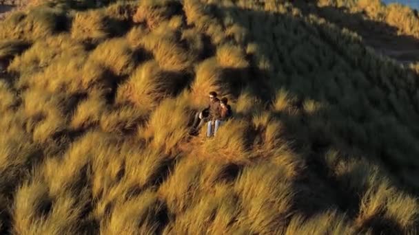 Jong koppel ligt op een heuvel en geniet van de zonsondergang — Stockvideo