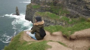 Cesur kızlar oturur İrlanda Moher uçurum kenarında