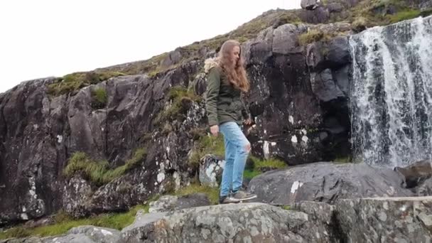 Menina bonita explora a paisagem maravilhosa em uma cachoeira na Irlanda — Vídeo de Stock