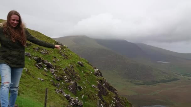 Junges Mädchen klettert über felsen in einem wunderschönen tal in irland — Stockvideo