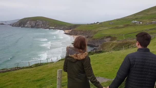 若い女性はアイルランドの海岸に沿って手をつないで歩く — ストック動画