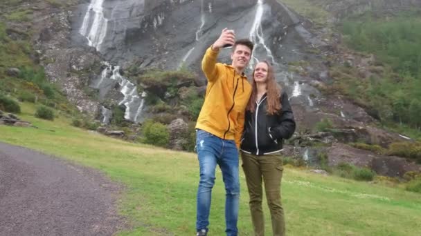 Молода пара унд його подорож по Ірландії приймає фотографії на водоспад Gleninchaquin — стокове відео