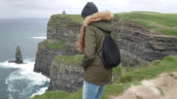 Giovane donna coraggiosa cammina fino al bordo delle ripide scogliere di Moher in Irlanda — Video Stock