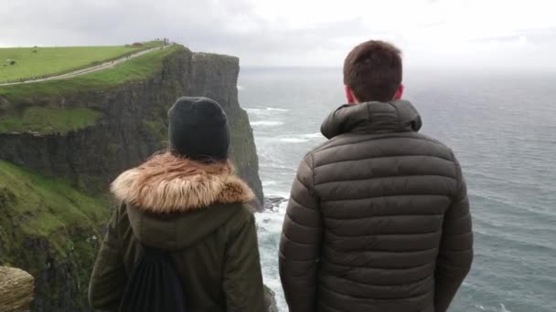 Junges paar auf seiner urlaubsreise nach irland ist beeindruckt von den klippen von moher — Stockvideo