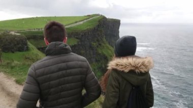 Genç çift Moher sarp uçurumların kenarında yürüyor