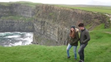 Genç çift Moher kayalıklarla İrlandalı Batı sahilinde nefes kesen sahne sahiptir