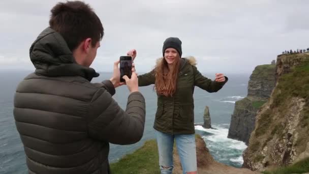 Mooi meisje is poseren voor haar vriendje op de Cliffs of Moher in Ierland — Stockvideo