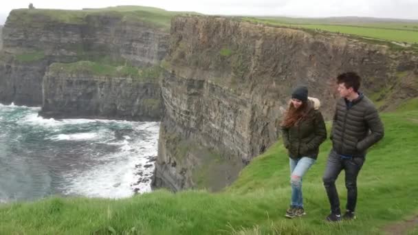 Junges paar auf seiner reise zu den berühmtesten sehenswürdigkeiten irlands - klippen von moher — Stockvideo