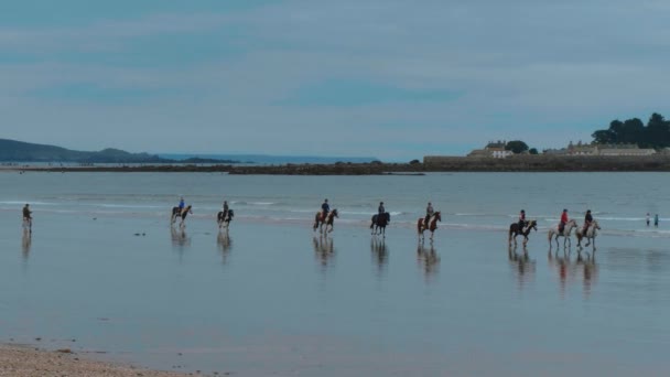 Orang-orang menunggang kuda di pantai Marazion di Cornwall — Stok Video