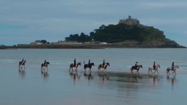 People Riding On Horses Over The Beach Of Marazion In Cornwall