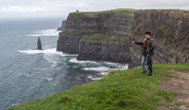 Genç çift dik kayalıklarla Moher İrlanda kenarında duruyor