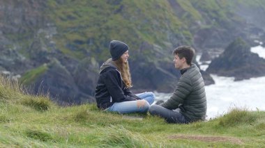 İki arkadaş çim uçuruma üstüne oturup