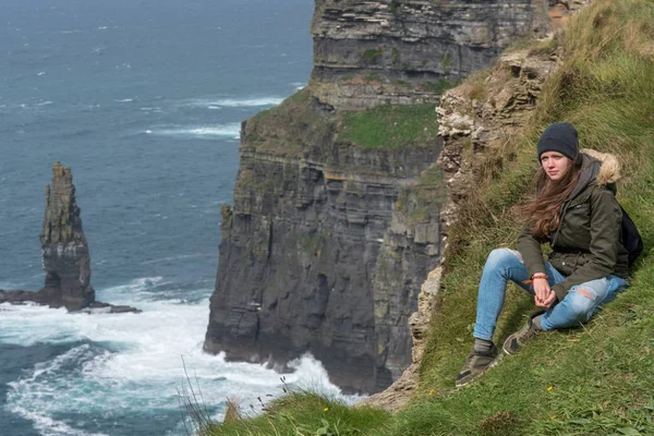 Girl sits on the edge of the steep Cliffs of Moher in Ireland — Stock Photo, Image