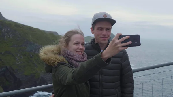 Dos jóvenes toman fotos y selfies en los acantilados de Kerry — Foto de Stock