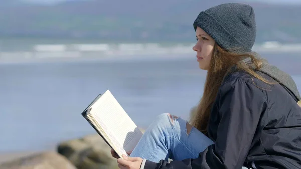 Jovem relaxa enquanto lê um livro na natureza — Fotografia de Stock