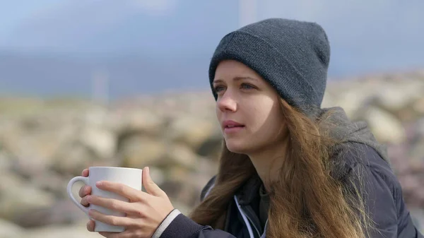 Красива дівчина сидить сама в океані і п'є чашку кави — стокове фото