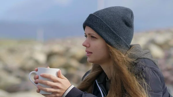 Mooi meisje zit alleen op de Oceaan en een kopje koffie drinkt — Stockfoto