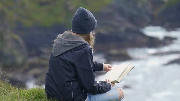 Jovem lê um livro enquanto relaxa à beira-mar — Fotografia de Stock